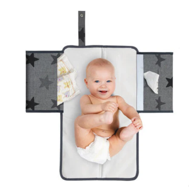 Baby ligger på utfälld Dooky 3-i-1 skötmatta med sidofack.